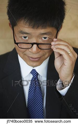 Senior Asian businessman pulling down his eyeglasses View Large Photo Image Stock Photography - Senior Asian businessman pulling down his eyeglasses. Fotosearch