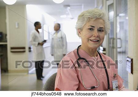 Stock Photo - Senior female nurse with doctors in background, Bethesda, Maryland, United States. Fotosearch