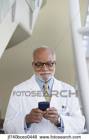Senior male African doctor using electronic organizer View Large Photo Image Stock Photo - Senior male African doctor using electronic organizer. Fotosearch