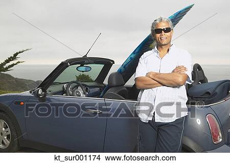 Senior man leaning on a convertible with a surfboard in it, Oakland, California, United States View Large Photo Image Picture - Senior man leaning on a convertible with a surfboard in it, Oakland, California, United States. Fotosearch