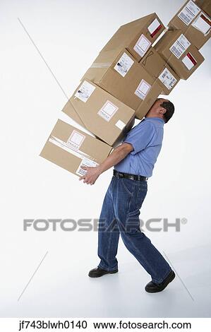 Stock Image - Studio shot of male warehouse worker carrying packages. Fotosearch