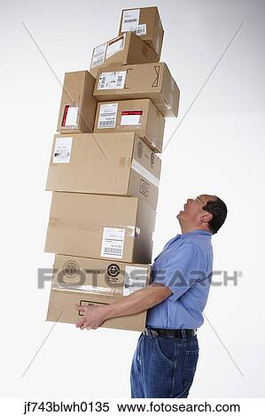 Stock Photography - Studio shot of male warehouse worker carrying packages. Fotosearch