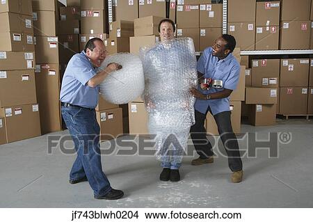 Picture - Three male warehouse workers joking around. Fotosearch