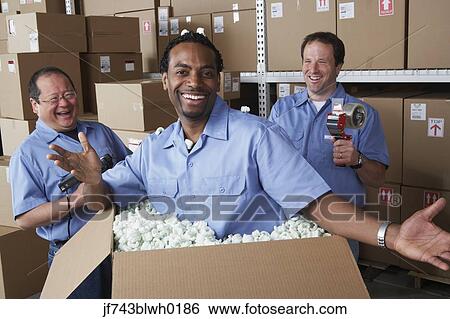 Stock Photograph - Three male warehouse workers joking around. Fotosearch