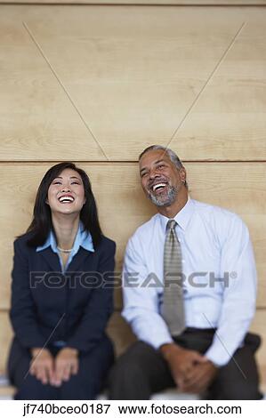 Two co-workers sitting and laughing View Large Photo Image Stock Photo - Two co-workers sitting and laughing. Fotosearch