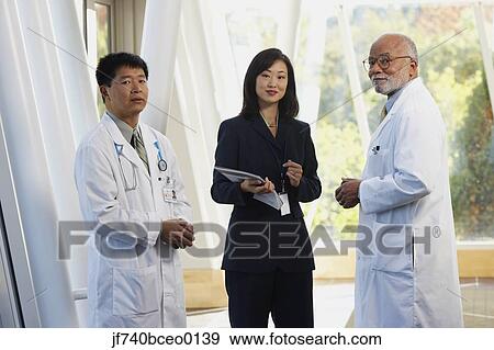 Two male doctors talking to Asian businesswoman, North Bethesda, Maryland, United States View Large Photo Image Stock Photo - Two male doctors talking to Asian businesswoman, North Bethesda, Maryland, United States. Fotosearch