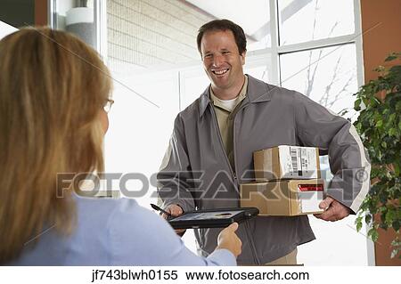 Stock Photography - Woman signing for packages from deliveryman. Fotosearch