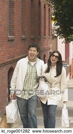 Stock Image - Young Asian couple walking down the sidewalk with shopping bags, San Francisco, California, United States. Fotosearch