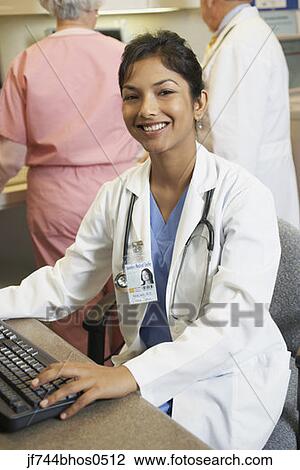 Stock Image - Young Indian female doctor at computer, Bethesda, Maryland, United States. Fotosearch