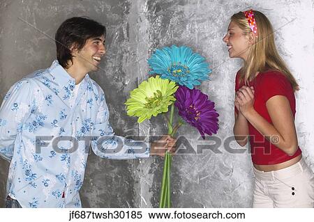 Young man giving young woman large flowers View Large Photo Image Stock Photography - Young man giving young woman large flowers. Fotosearch