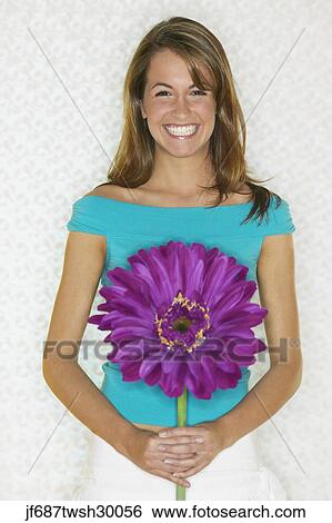 Young woman smiling and holding large flower View Large Photo Image Stock Photograph - Young woman smiling and holding large flower. Fotosearch