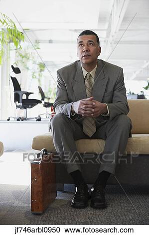 Stock Image - African American businessman sitting in waiting area. Fotosearch