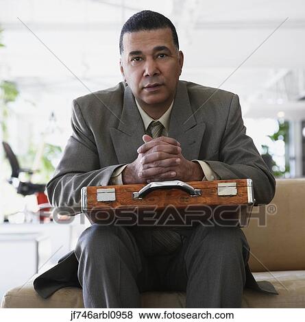 Stock Photo - African American businessman sitting in waiting area. Fotosearch