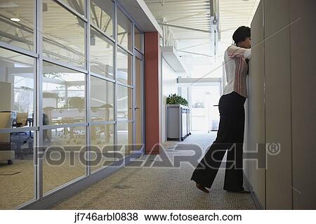 Stock Photo - African American businesswoman leaning over cubicle wall. Fotosearch