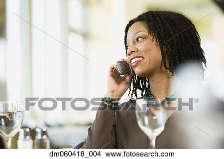 Picture - African American businesswoman on cell phone in restaurant. Fotosearch