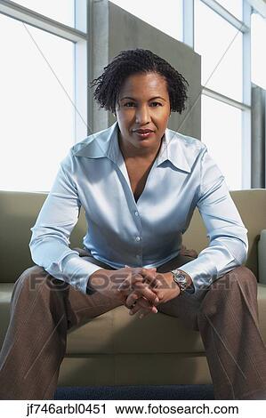 Stock Image - African American businesswoman sitting on sofa. Fotosearch