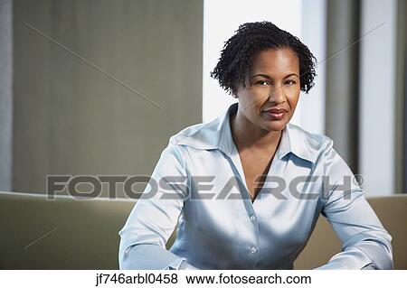 Stock Photo - African American businesswoman sitting on sofa. Fotosearch