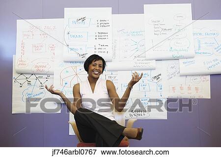 Stock Photo - African American businesswoman sitting in front of wall charts. Fotosearch