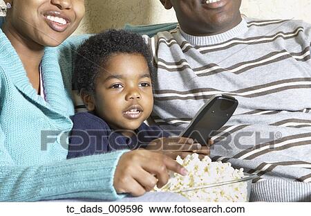 Stock Photograph - African American family watching television with popcorn. Fotosearch