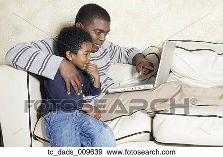 African American father and young son with laptop on sofa View Large Photo Image Stock Photo - African American father and young son with laptop on sofa. Fotosearch