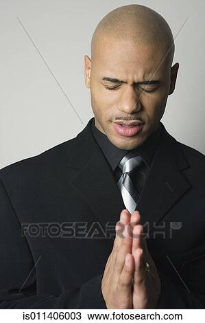 Stock Image - African American man in suit praying. Fotosearch