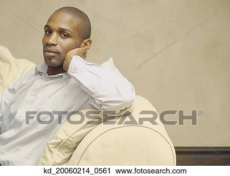 African American man sitting on sofa View Large Photo Image Stock Image - African American man sitting on sofa. Fotosearch