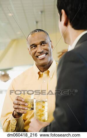 Stock Photograph - African American man with drink talking to friend. Fotosearch