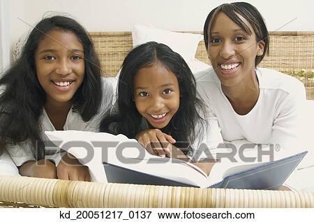 African American mother and daughters on bed with book View Large Photo Image Stock Photo - African American mother and daughters on bed with book. Fotosearch