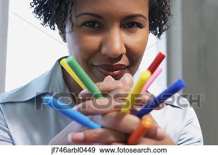Stock Photo - African American woman holding multicolored markers in hands. Fotosearch