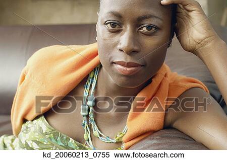 Stock Photography - African American woman sitting on sofa. Fotosearch