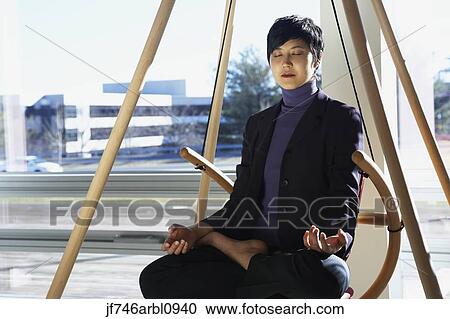 Stock Image - Asian businesswoman meditating. Fotosearch