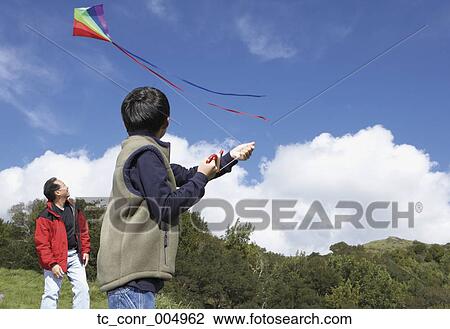 Stock Image - Asian father and son flying a kite . Fotosearch
