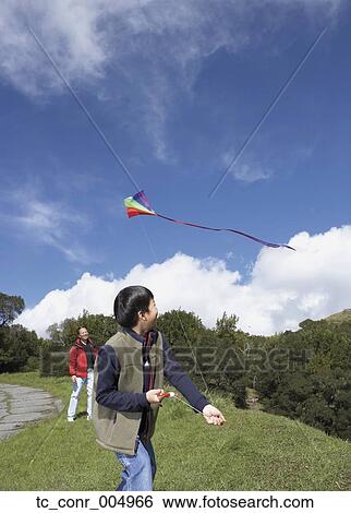 Stock Photograph - Asian father and son flying a kite . Fotosearch
