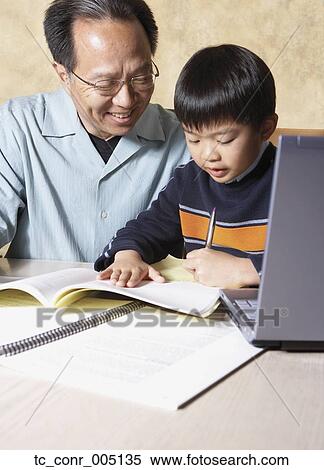 Stock Photography - Asian father helping young son with homework. Fotosearch