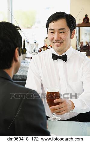 Asian male bartender serving man drink at bar View Large Photo Image Stock Image - Asian male bartender serving man drink at bar. Fotosearch