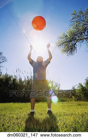 Stock Photo - Boy throwing ball in bright sunlight. Fotosearch