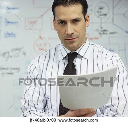 Businessman reading paperwork in front of whiteboard View Large Photo Image Stock Photo - Businessman reading paperwork in front of whiteboard. Fotosearch