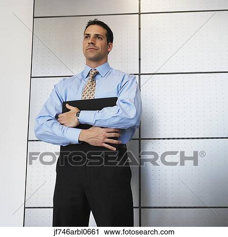 Stock Image - Businessman standing in front of wall. Fotosearch