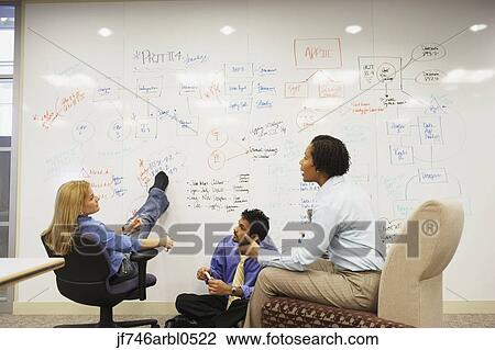 Stock Image - Businesspeople having a meeting in front of a whiteboard wall. Fotosearch