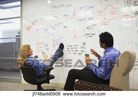 Businesspeople having a meeting in front of a whiteboard wall View Large Photo Image Stock Photo - Businesspeople having a meeting in front of a whiteboard wall. Fotosearch