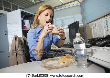 Businesswoman eating lunch at desk View Large Photo Image Stock Photo - Businesswoman eating lunch at desk. Fotosearch