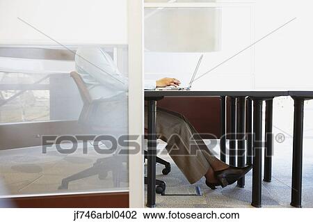 Stock Image - Businesswoman sitting at desk with laptop. Fotosearch