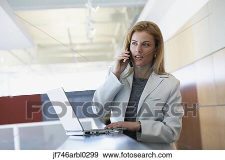 Stock Photo - Businesswoman with laptop and cell phone. Fotosearch