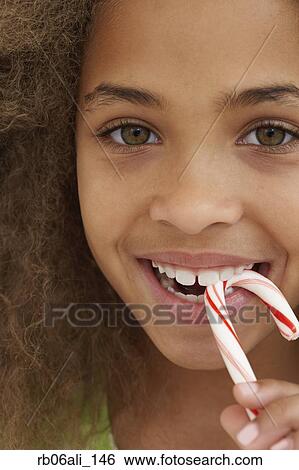 Close up of African American girl eating candy cane View Large Photo Image Stock Photograph - Close up of African American girl eating candy cane. Fotosearch