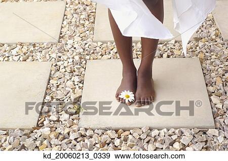 Stock Photo - Close up of African American woman's bare feet with flower. Fotosearch