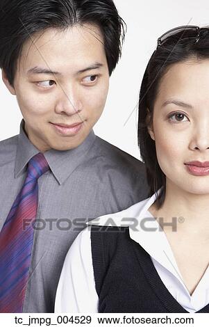 Stock Photo - Close up of Asian businessman looking at Asian businesswoman. Fotosearch