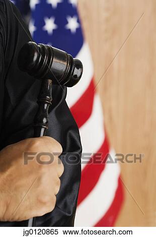 Stock Photography - Close up of male African judge's hand holding gavel. Fotosearch