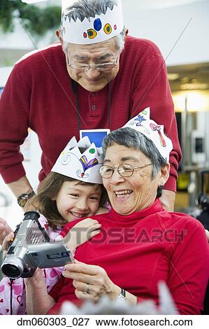 Grandparents and granddaughter looking at videocamera View Large Photo Image Stock Photo - Grandparents and granddaughter looking at videocamera. Fotosearch