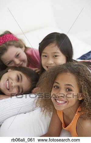 Group of young girls lying on bed View Large Photo Image Stock Image - Group of young girls lying on bed. Fotosearch