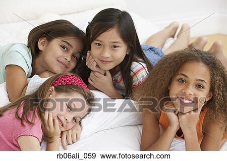 Group of young girls lying on bed View Large Photo Image Stock Photo - Group of young girls lying on bed. Fotosearch